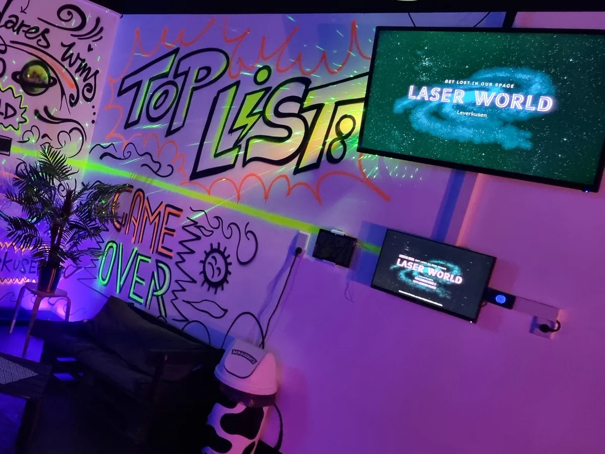 Lounge der Laser World Leverkusen mit Graffiti an den Wänden und Bildschirmen mit dem Logo